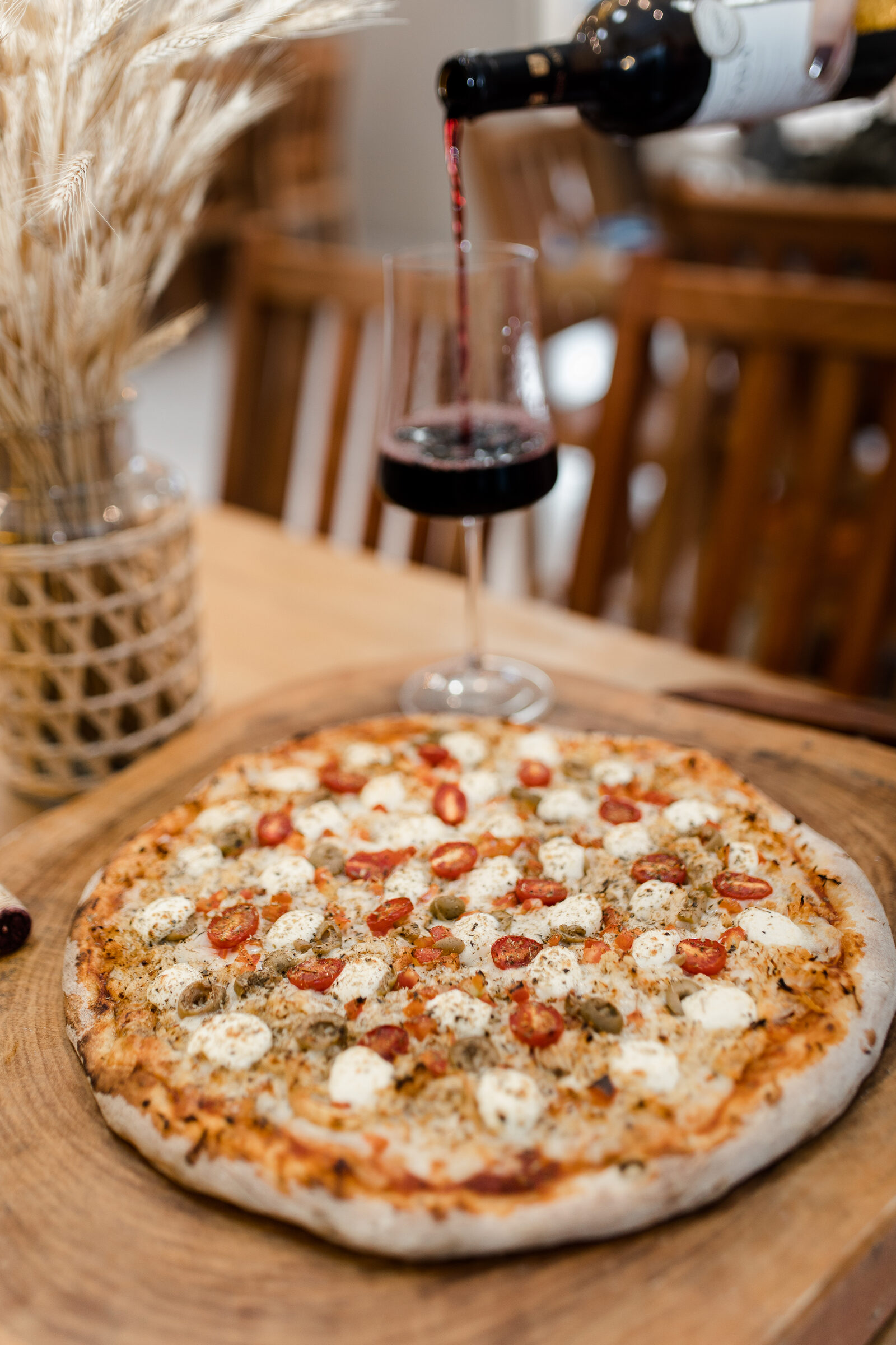 Pizza da Cia Casero na tábua, no salão, com o vinho sendo servido