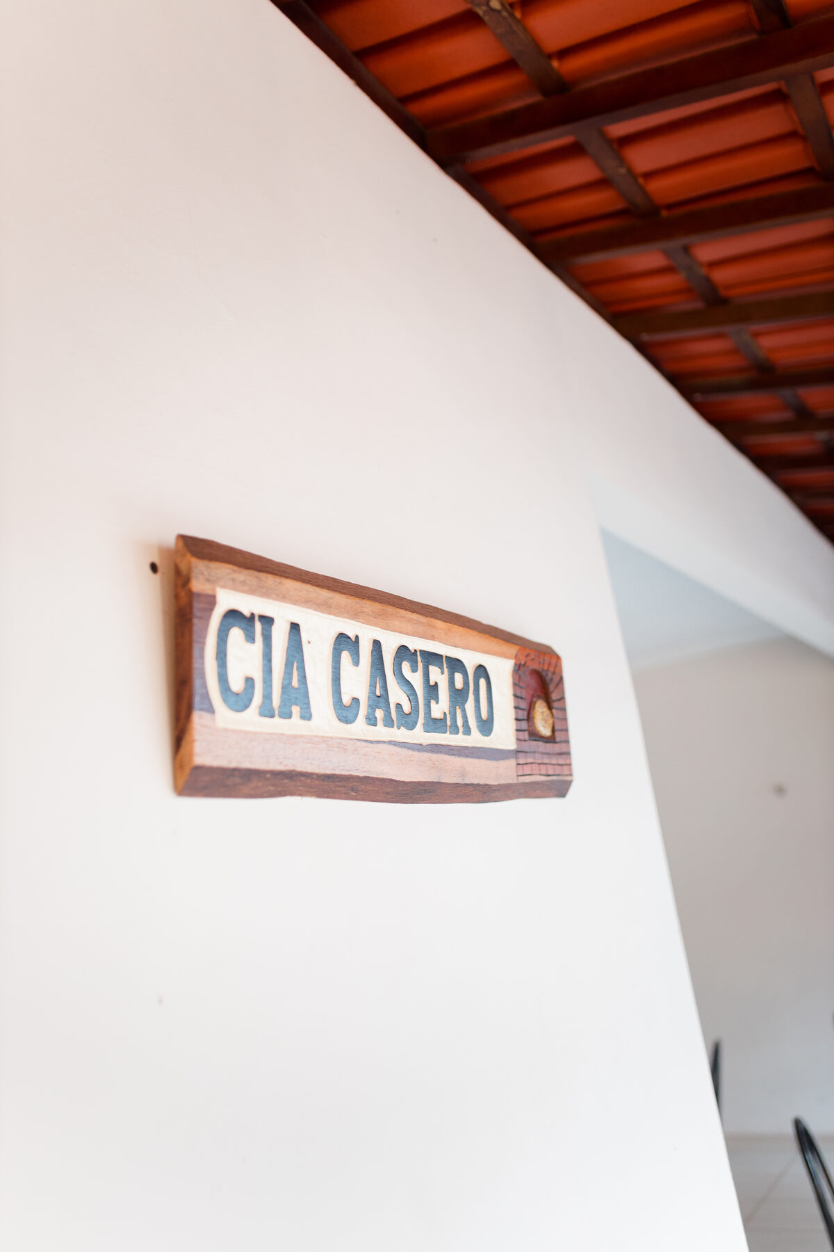 Placa de madeira com o nome Cia Casero na parede da casa